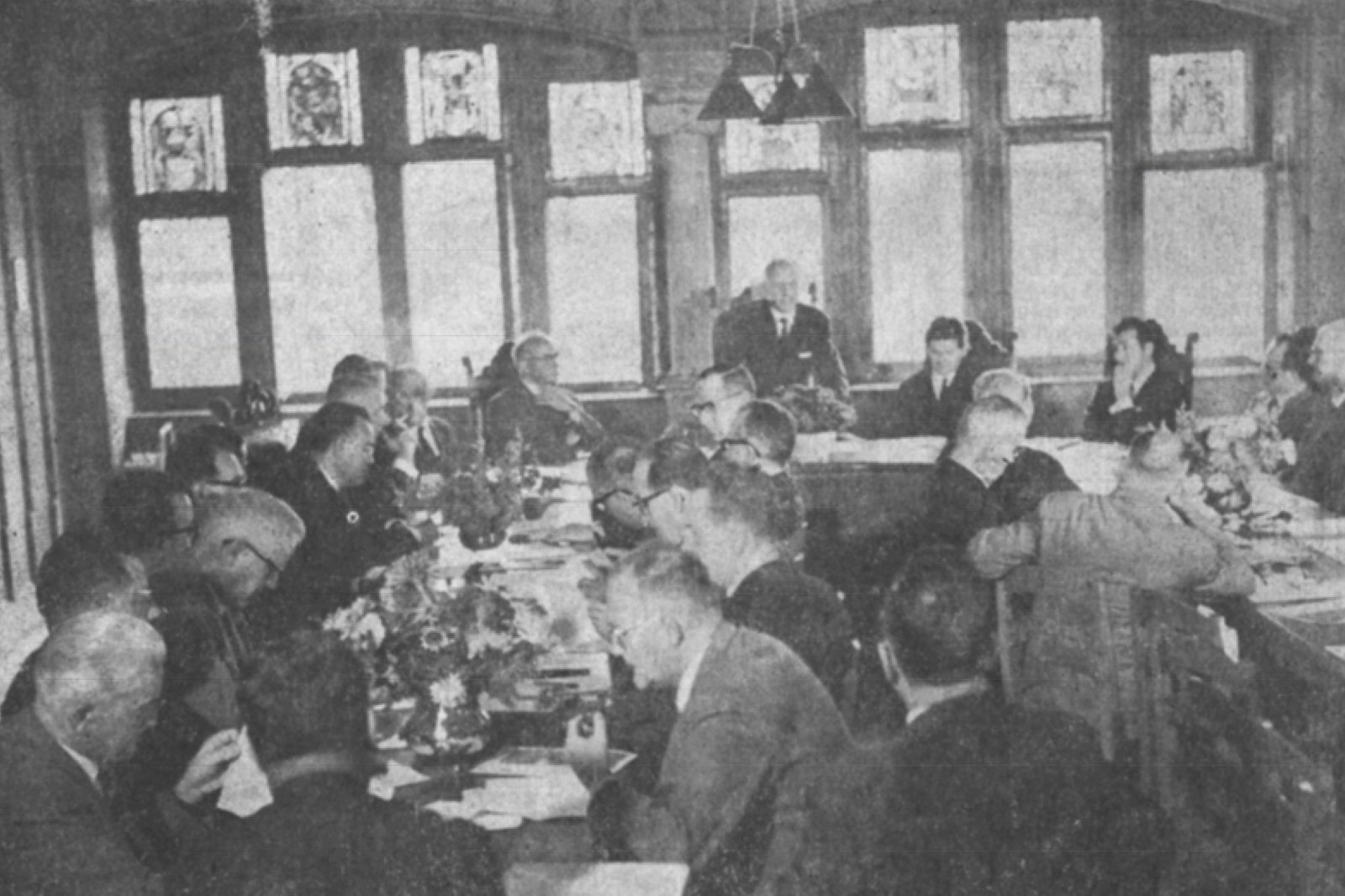 Una ventina di uomini di una certa età ascoltano l’oratore seduti attorno a dei tavoli disposti a U.